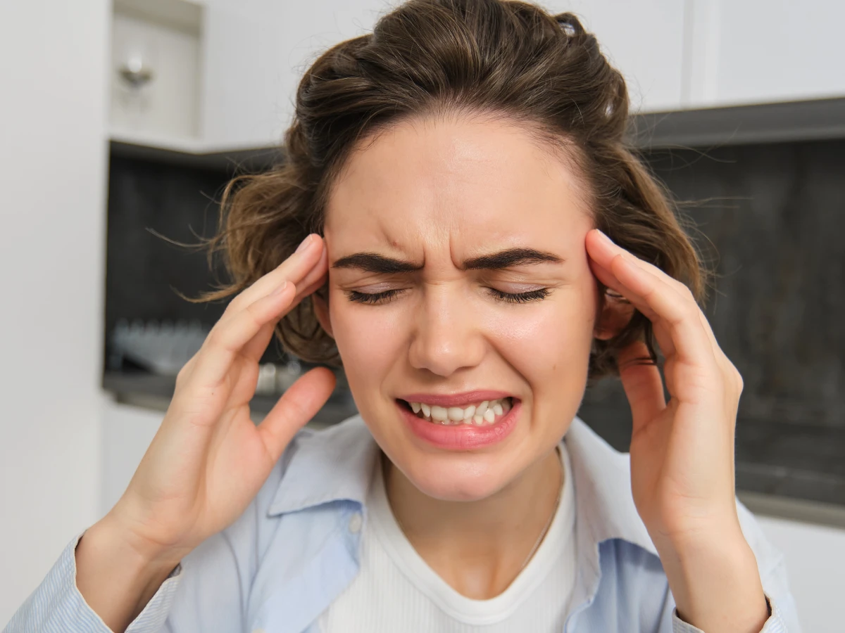 mujer que sufre de dolor de cabeza y rechina los dientes